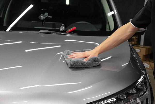 A man wiping a grey car hood with a towel. Showing the care to detail that Andy's Autowash shows.