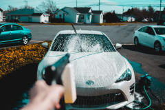 Image of someone washing their car at home in their driveway.