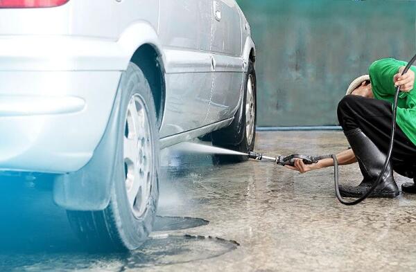 Cleaning under a car with power washer showing the importance having the undercarriage of your car washed by a professional like at Andy's Autowash.