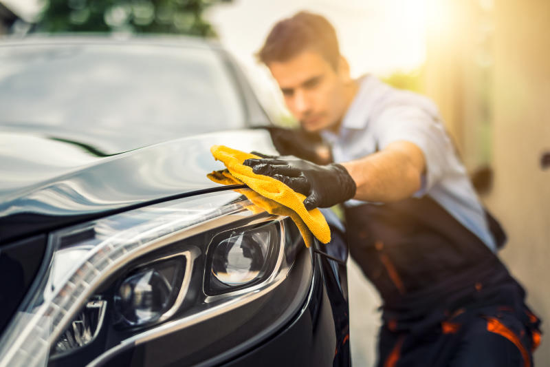 Professional Car Detailer (Andy's Auto Wash) gently washing automobile exterior for scratch-free cleaning.
