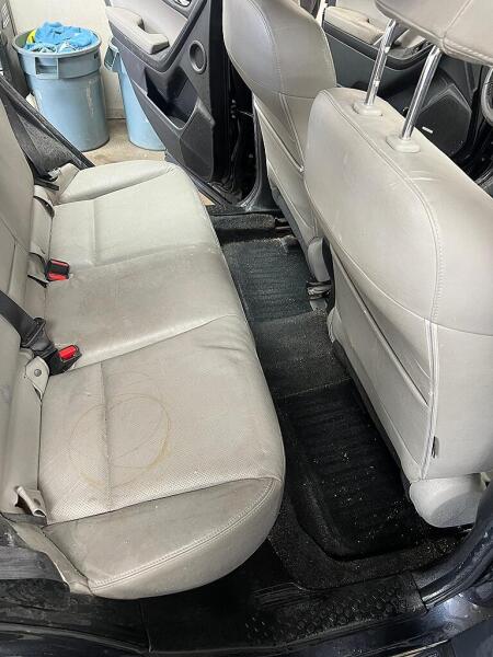 The backseats of the SUV before the detailing service by Andy's Autowash. There is dirt on the floor boards and seats.