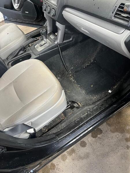 The front passenger's side floor board carpet that is covered in dirt before the interior detailing by Andy's Autowash.