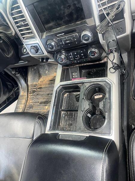 A close-up of the dirty middle console and cupholders of an F350 before it has had interior detailing by Andy's Autowash.