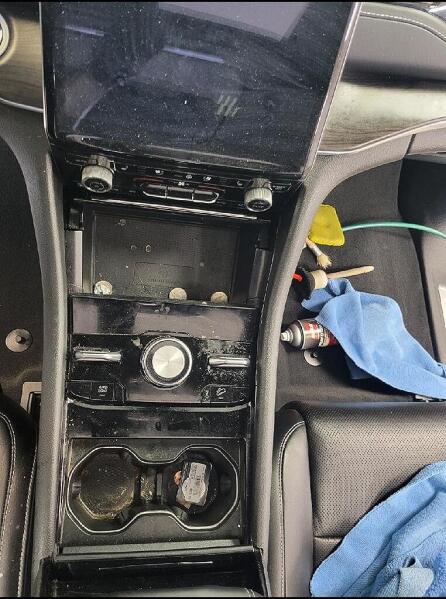 The center console of the inside a car before it had an interior detailing service by Andy's Autowash and Detailing.