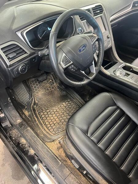 The front drivers side of a Ford vehicle before it was cleaned by Andy's Autowash. Showing all the debris and dirt on the floorboards.