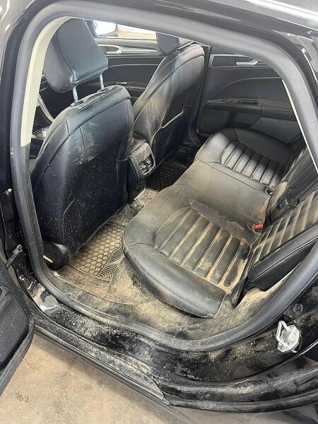 The rear drivers side seat of a Ford car before it was cleaned by Andy's Autowash. Showing the debris on the floor & seat.